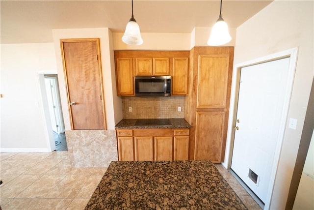 2033 Briarwood Dr, Corpus Christi, TX 78412 - kitchen featuring stainless steel microwave, tasteful backsplash, decorative light fixtures, dark stone counters, and brown cabinets