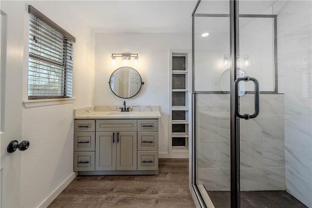 bathroom featuring a stall shower, baseboards, wood finished floors, and vanity