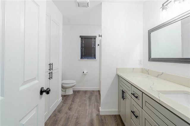 bathroom featuring baseboards, vanity, toilet, and wood finished floors