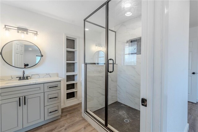 full bath featuring vanity, wood finished floors, and a marble finish shower