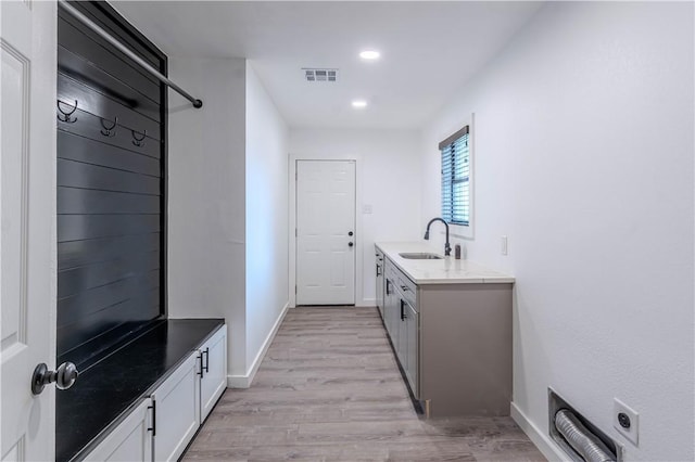 laundry area featuring baseboards, visible vents, light wood-style floors, a sink, and recessed lighting