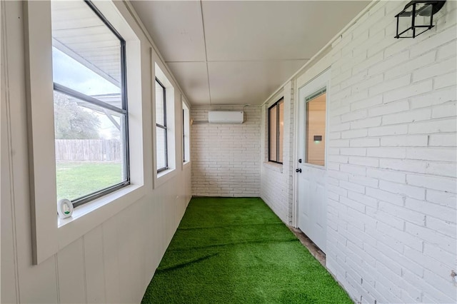 hall with dark colored carpet, brick wall, and a wall mounted AC