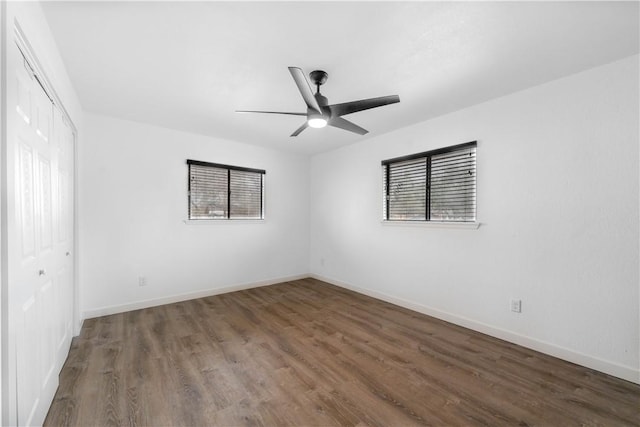 empty room with baseboards, ceiling fan, wood finished floors, and a healthy amount of sunlight