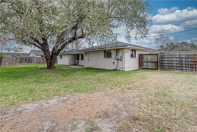 rear view of house with a yard, brick siding, and a fenced backyard