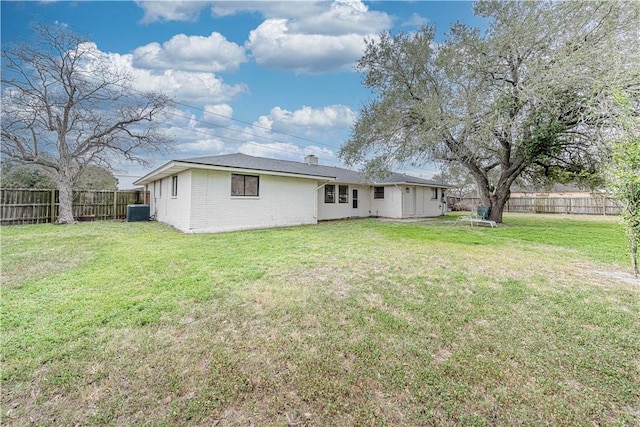 rear view of property with brick siding, a fenced backyard, central AC unit, and a yard