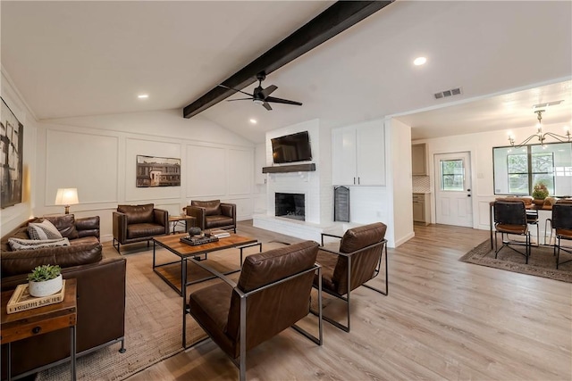 living room with lofted ceiling with beams, a fireplace, visible vents, and a decorative wall