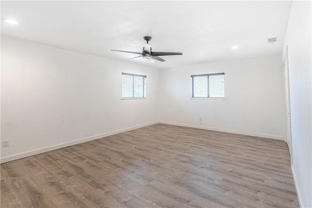 empty room with recessed lighting, wood finished floors, a ceiling fan, visible vents, and baseboards