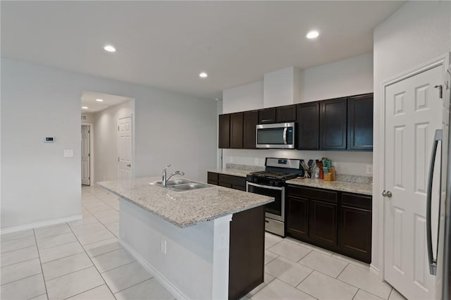 kitchen featuring sink, light stone counters, a center island with sink, light tile patterned floors, and appliances with stainless steel finishes