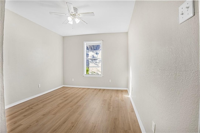 spare room with ceiling fan, light wood-style flooring, and baseboards