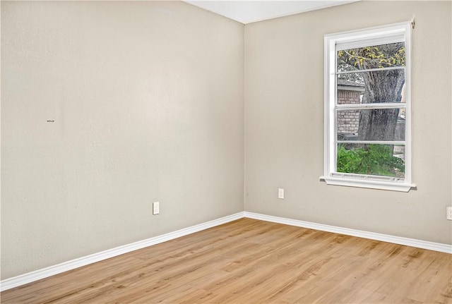 spare room featuring plenty of natural light, baseboards, and wood finished floors