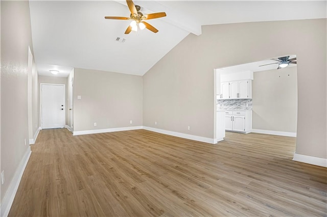 unfurnished living room with lofted ceiling with beams, light wood-style flooring, a ceiling fan, and baseboards