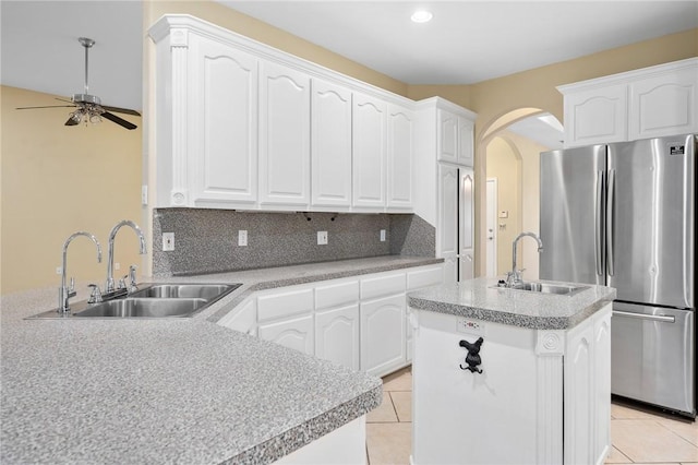 kitchen featuring white cabinetry, sink, a center island with sink, and stainless steel fridge