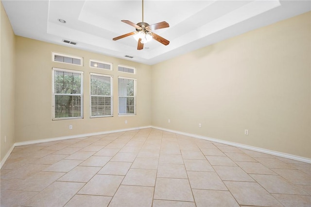 unfurnished room with light tile patterned floors, ceiling fan, and a tray ceiling