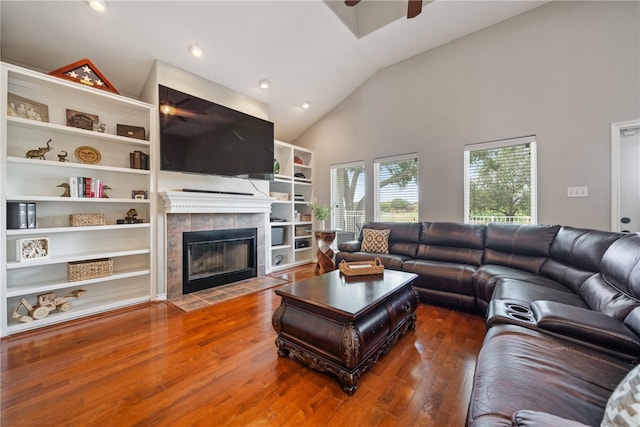 living room featuring high vaulted ceiling, a tile fireplace, hardwood / wood-style flooring, and ceiling fan