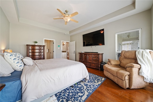 bedroom with a tray ceiling, ceiling fan, and dark hardwood / wood-style floors