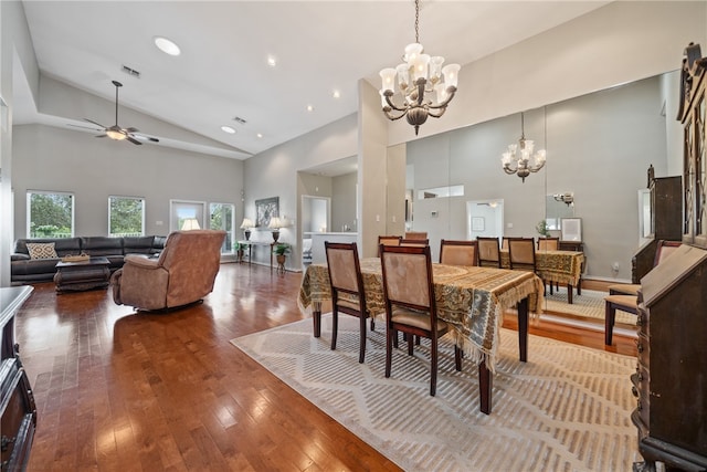 dining area with hardwood / wood-style flooring, ceiling fan with notable chandelier, and high vaulted ceiling