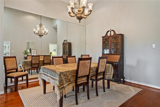 dining area with a high ceiling, an inviting chandelier, and hardwood / wood-style floors