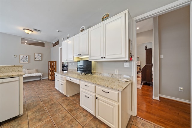 kitchen featuring light stone counters, white dishwasher, dark hardwood / wood-style floors, white cabinetry, and built in desk