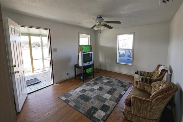 sitting room featuring ceiling fan, dark hardwood / wood-style floors, plenty of natural light, and a textured ceiling