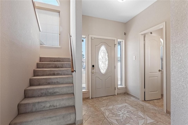 foyer entrance featuring stairs and baseboards