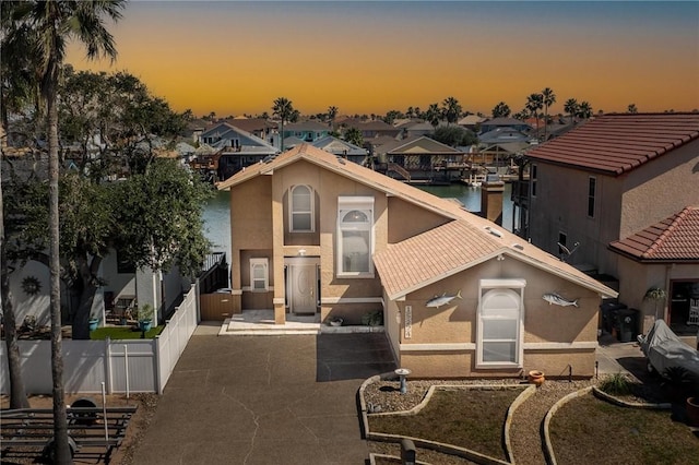 view of front of property featuring a residential view, fence, a tiled roof, and stucco siding