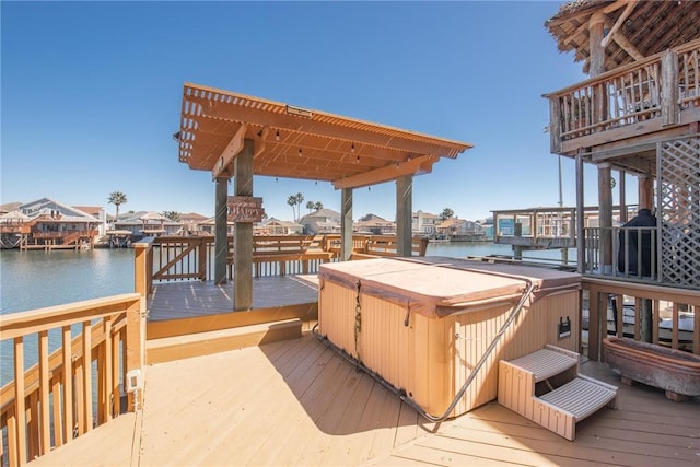 wooden terrace featuring a water view and a hot tub