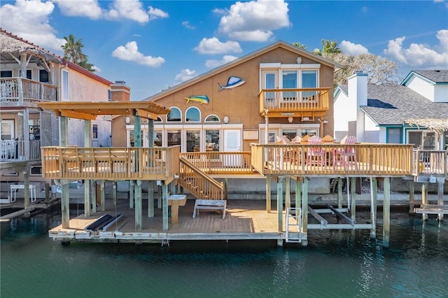 back of property featuring a chimney, a deck with water view, boat lift, and stucco siding