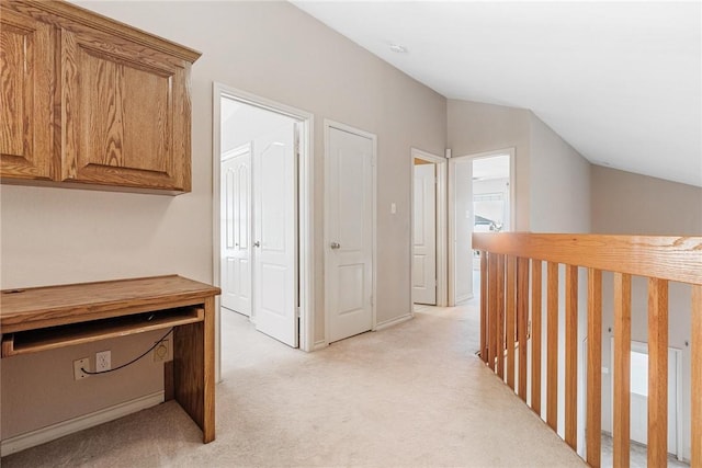 hallway with vaulted ceiling and light carpet