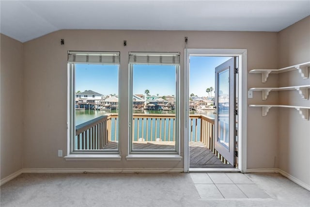 entryway featuring vaulted ceiling, carpet floors, a water view, and baseboards