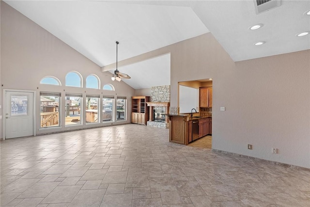 unfurnished living room with a fireplace, visible vents, a ceiling fan, a sink, and high vaulted ceiling