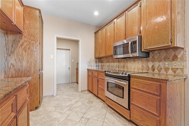 kitchen with stainless steel appliances, light stone counters, and decorative backsplash