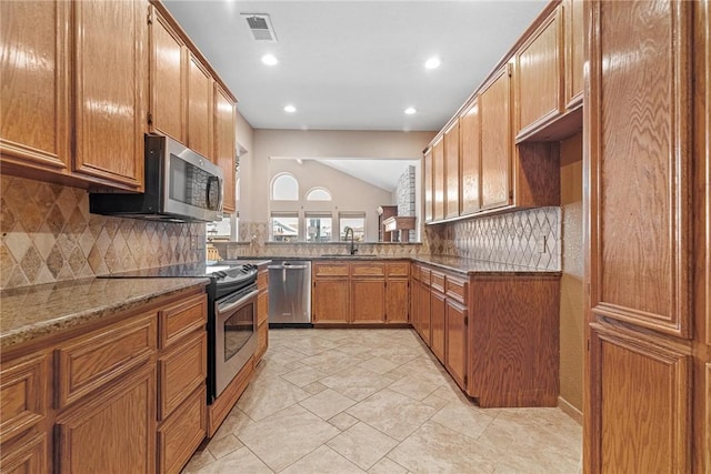 kitchen with lofted ceiling, a sink, visible vents, appliances with stainless steel finishes, and brown cabinets