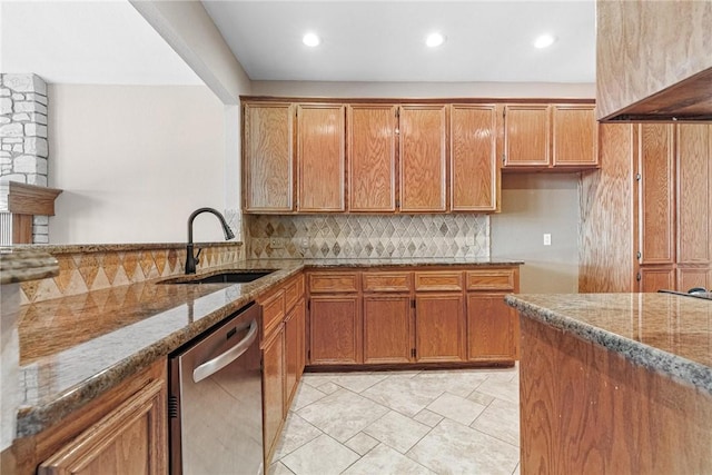 kitchen with light stone counters, brown cabinets, dishwasher, and a sink