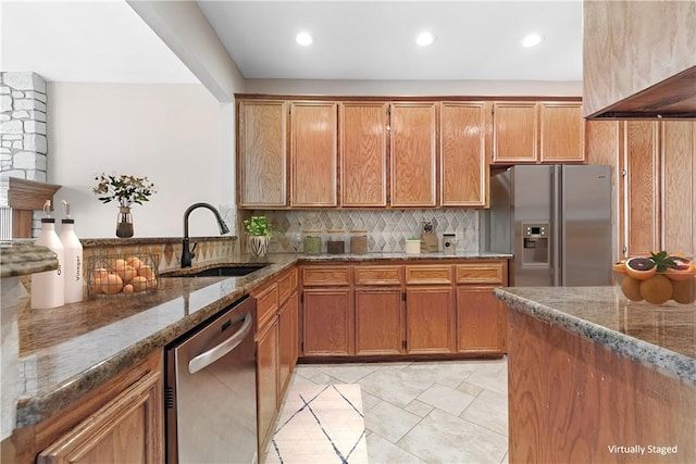 kitchen featuring decorative backsplash, stone counters, appliances with stainless steel finishes, and a sink