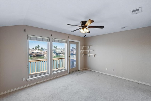 spare room with carpet floors, visible vents, a water view, a ceiling fan, and baseboards