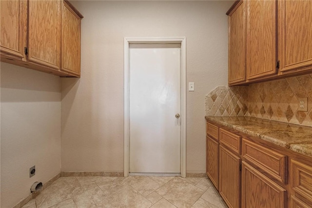 washroom with baseboards, cabinet space, and hookup for an electric dryer