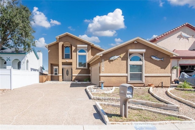 view of front of property featuring a garage, driveway, fence, and stucco siding