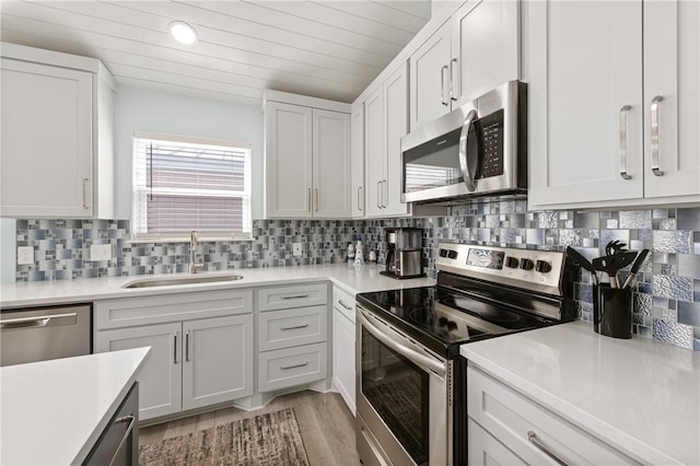 kitchen with sink, appliances with stainless steel finishes, tasteful backsplash, light hardwood / wood-style floors, and white cabinets