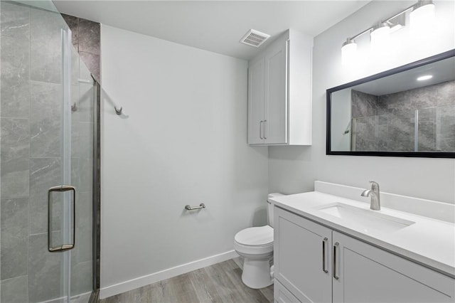 bathroom with vanity, hardwood / wood-style flooring, a shower with door, and toilet