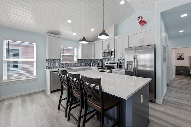 kitchen featuring sink, decorative light fixtures, a center island, a kitchen breakfast bar, and stainless steel appliances