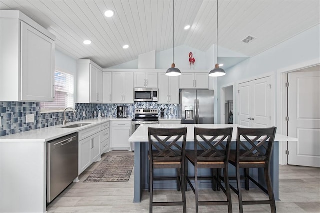 kitchen featuring sink, white cabinetry, decorative light fixtures, appliances with stainless steel finishes, and a kitchen breakfast bar