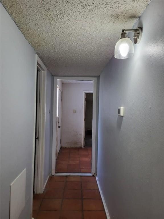 hallway with dark tile patterned floors and a textured ceiling