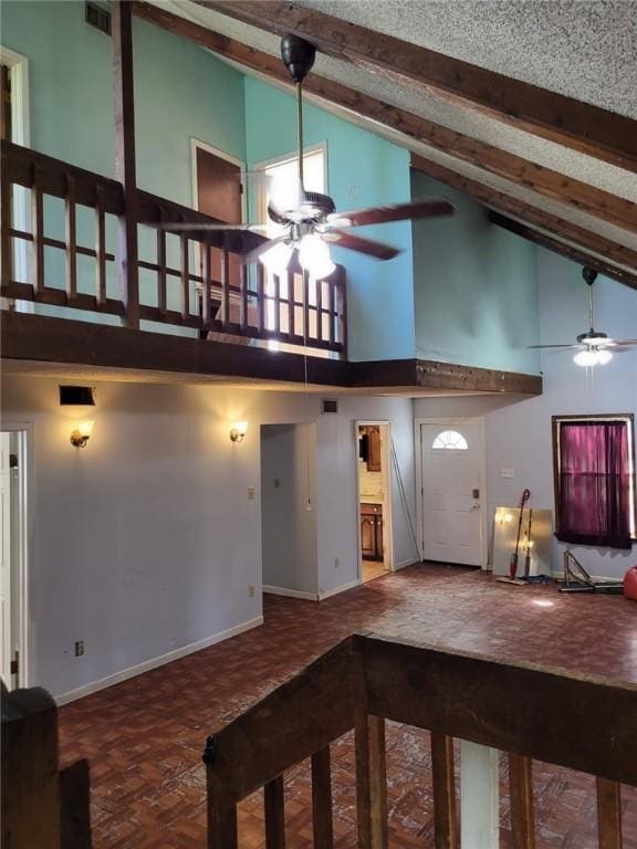 unfurnished living room featuring ceiling fan, beamed ceiling, high vaulted ceiling, and parquet flooring