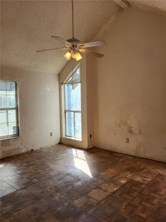 spare room with lofted ceiling with beams, ceiling fan, a healthy amount of sunlight, and a textured ceiling