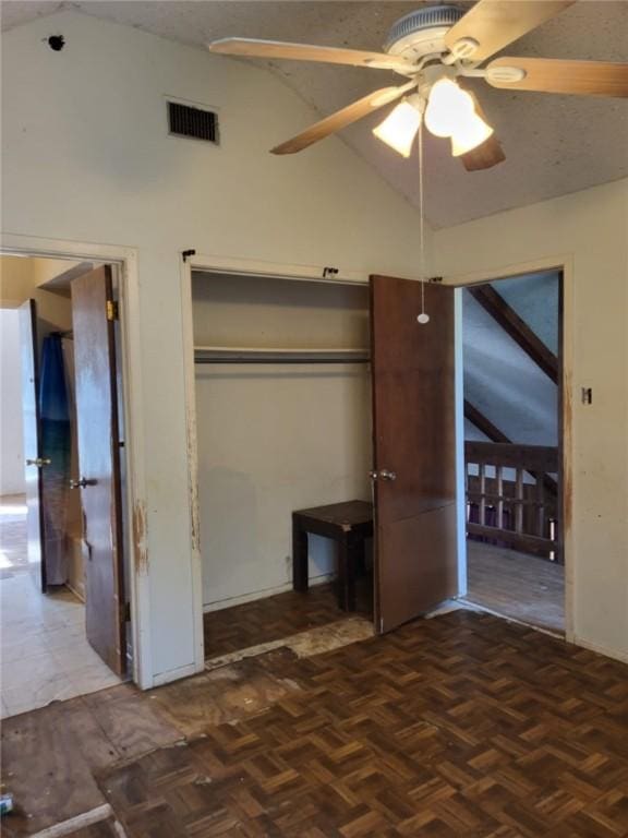 unfurnished bedroom with ceiling fan, lofted ceiling, and parquet flooring