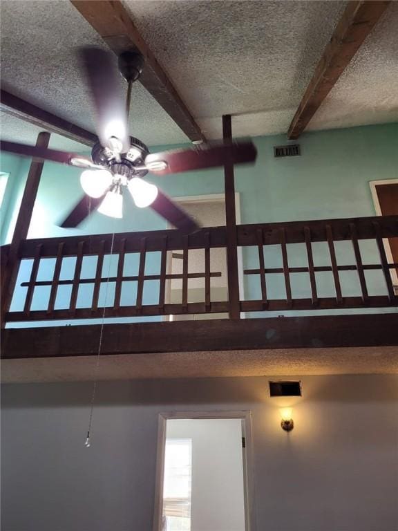 room details with beamed ceiling, ceiling fan, and a textured ceiling