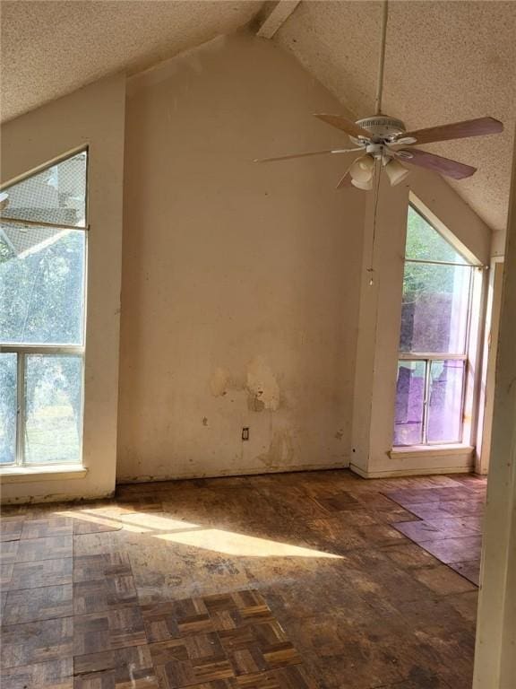 empty room featuring parquet flooring, a textured ceiling, vaulted ceiling with beams, and ceiling fan