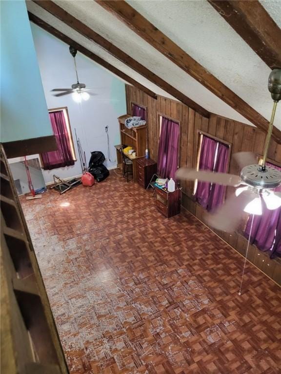 unfurnished living room featuring lofted ceiling with beams, ceiling fan, dark parquet floors, and wood walls