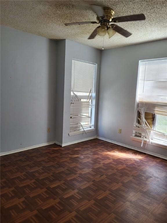 empty room with ceiling fan, dark parquet floors, and a textured ceiling