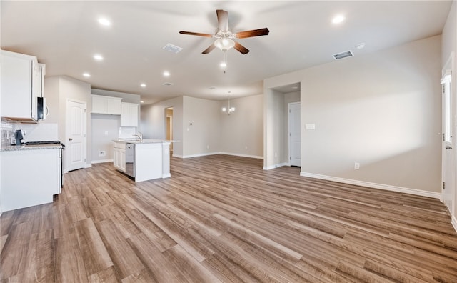 kitchen featuring visible vents, open floor plan, a center island with sink, and white cabinets